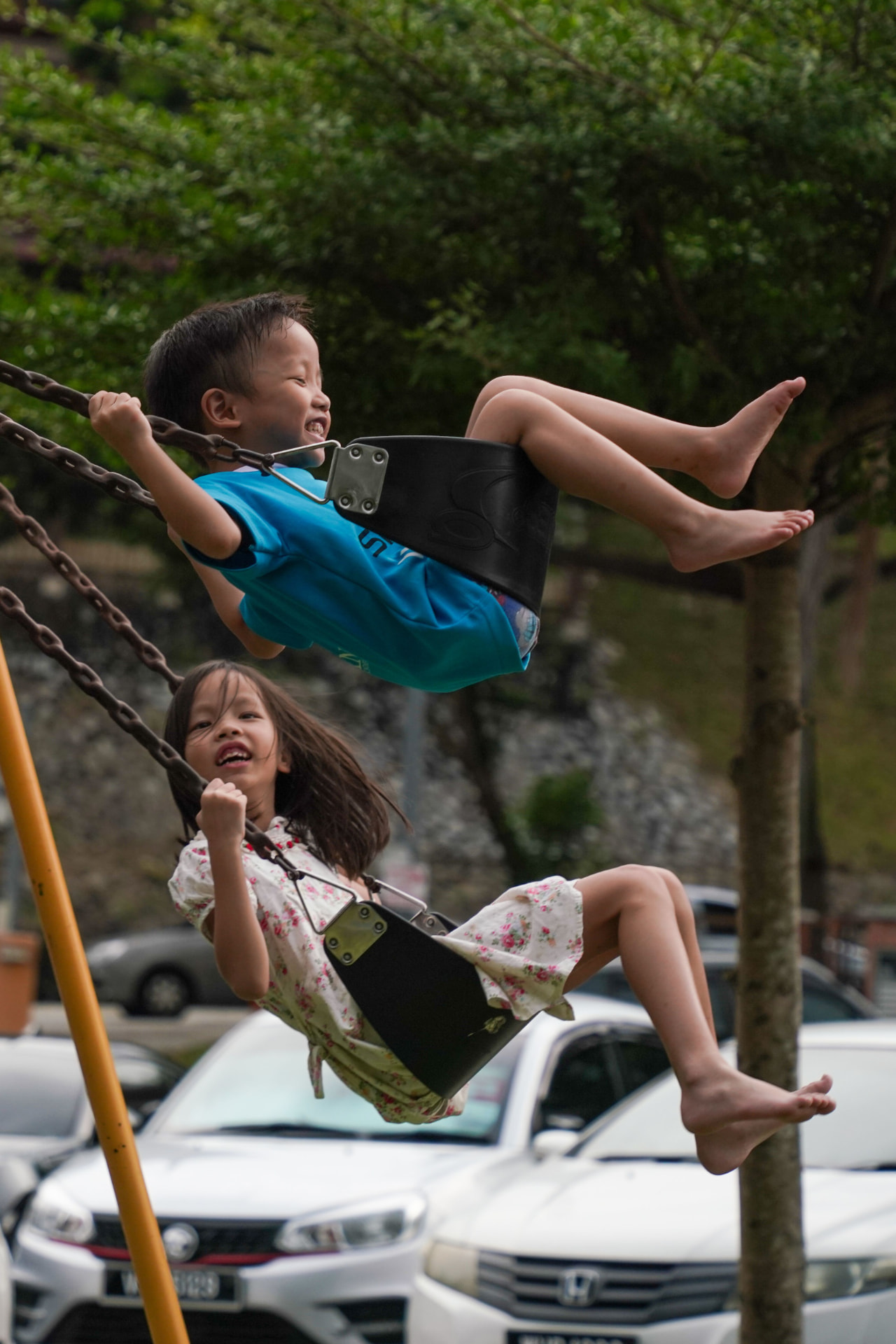 Two kids swinging side by side on a sunny afternoon