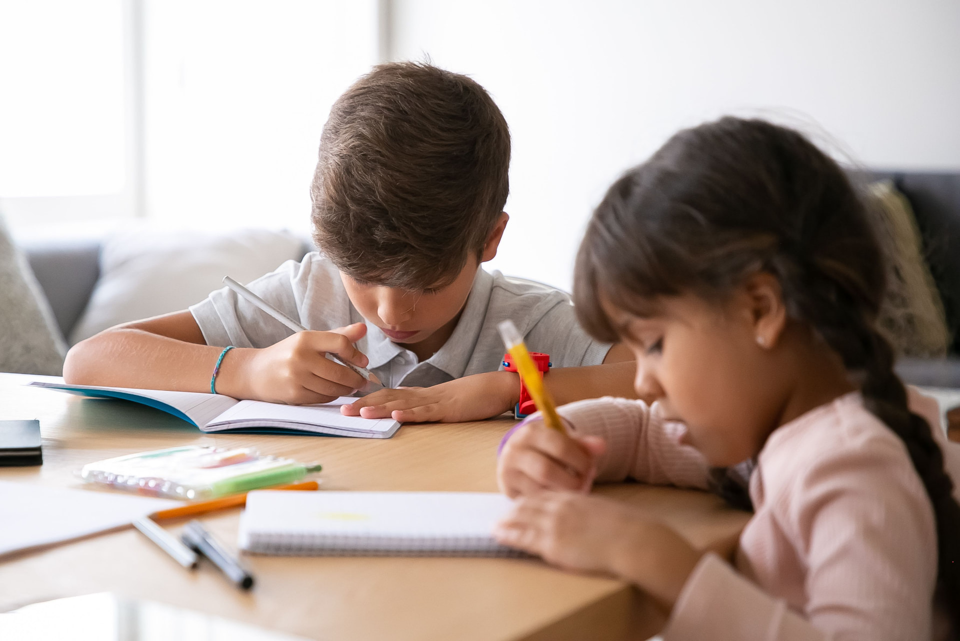 A brother and sister working through lessons together at the kitchen table